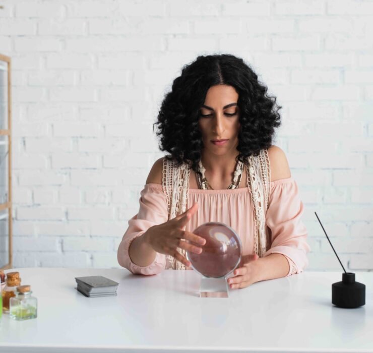 A focused astrologist with curly hair using a crystal ball, symbolizing the importance of looking beyond assumptions to understand customer problems.