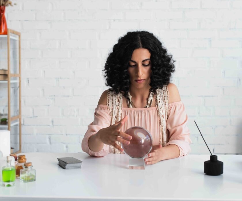 A focused astrologist with curly hair using a crystal ball, symbolizing the importance of looking beyond assumptions to understand customer problems.